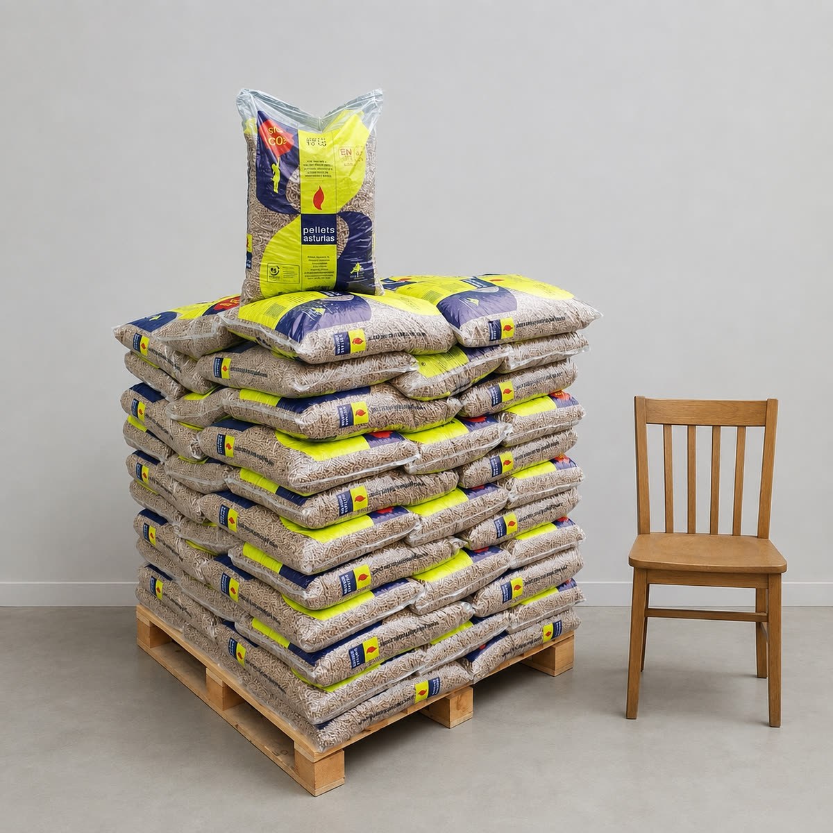 Palet de pellets Pellets Asturias junto a una silla, escala real